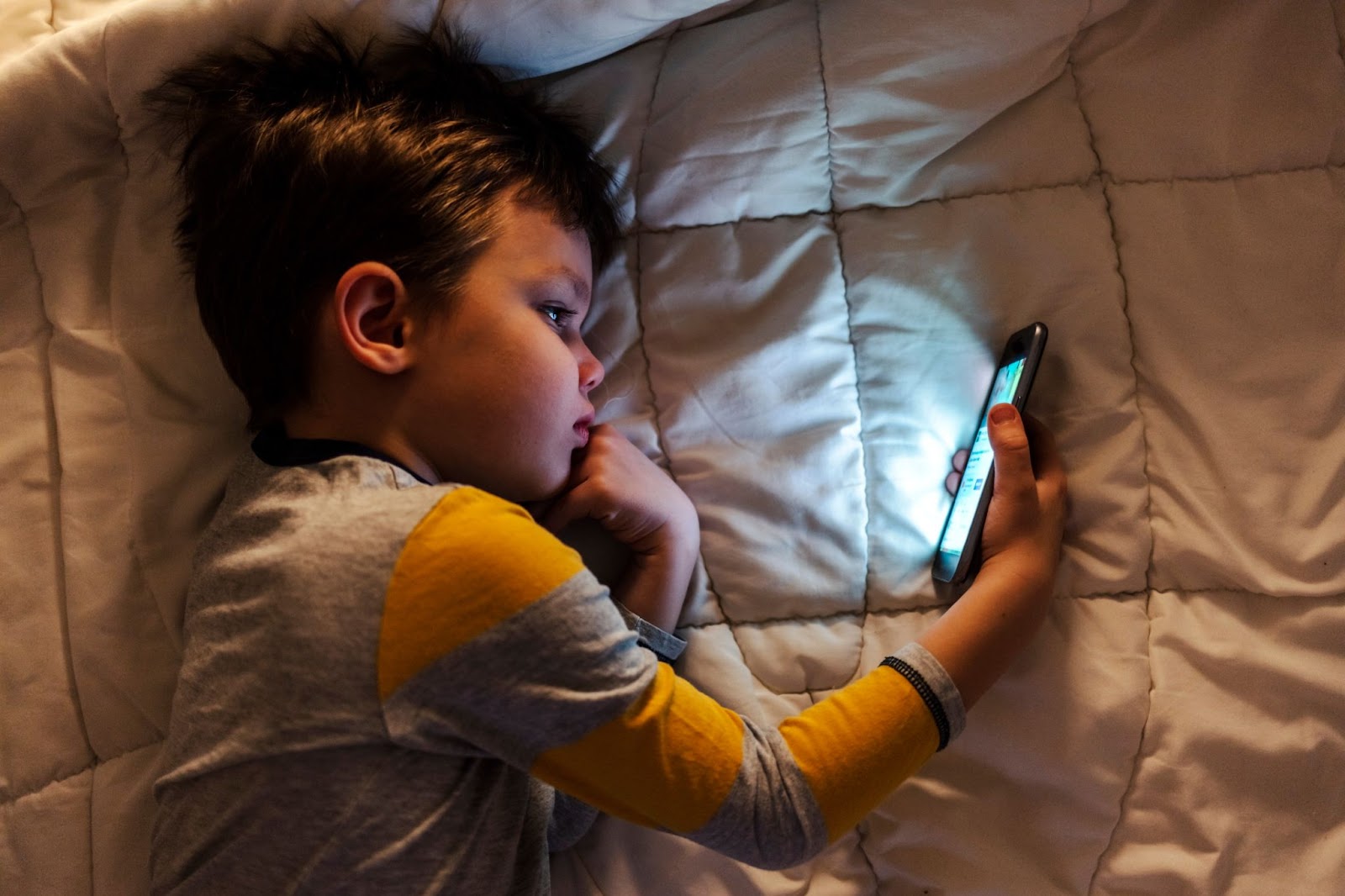 Мальчик сидит в телефоне вечером и пропускает лучшее время для сна
