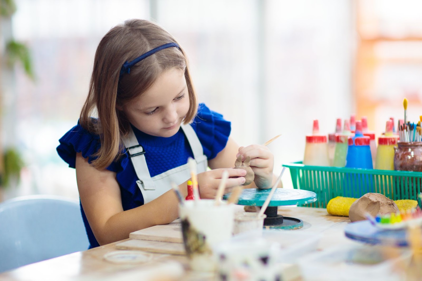 Девочка работает на гончарном круге. Детский урок декоративно-прикладного искусства в мастерской.
